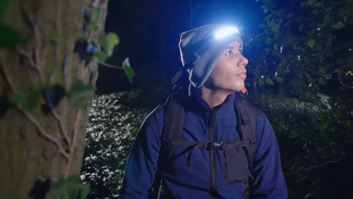 A hiker wears a headlamp while exploring the woods at night.
